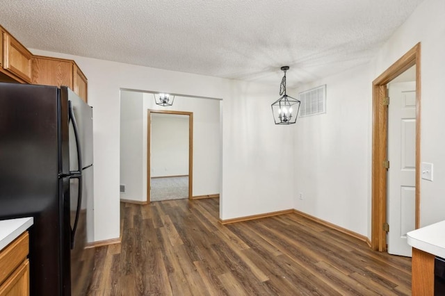 kitchen with decorative light fixtures, a textured ceiling, black refrigerator, dark hardwood / wood-style flooring, and a chandelier