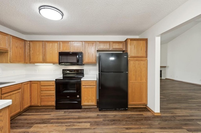 kitchen with black appliances, dark wood-type flooring, sink, and a textured ceiling