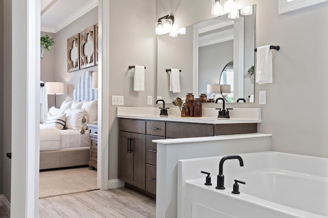 bathroom featuring a washtub, hardwood / wood-style floors, vanity, and ornamental molding