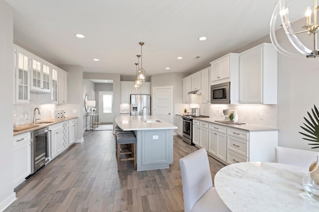 kitchen with white cabinetry, an island with sink, stainless steel appliances, and wine cooler