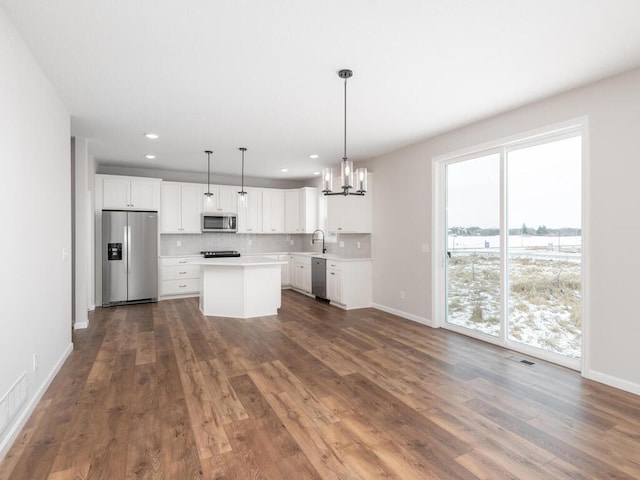 kitchen featuring dark hardwood / wood-style floors, a center island, pendant lighting, white cabinetry, and appliances with stainless steel finishes