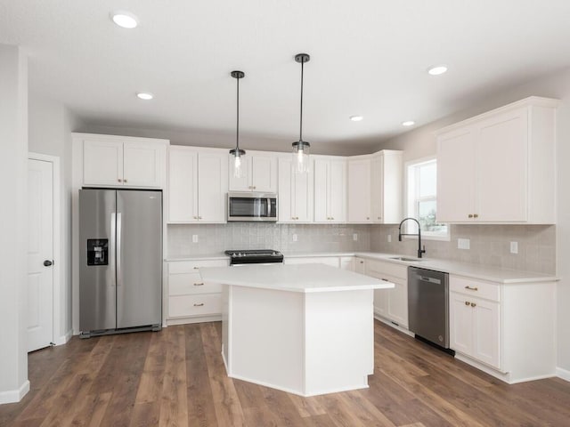 kitchen featuring white cabinets, hanging light fixtures, appliances with stainless steel finishes, and a center island