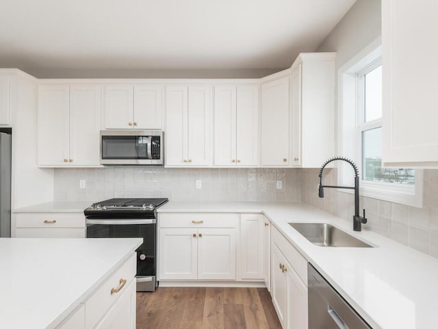 kitchen featuring tasteful backsplash, appliances with stainless steel finishes, sink, and white cabinetry