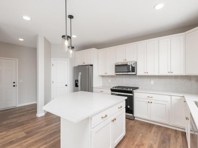 kitchen with appliances with stainless steel finishes, a center island, white cabinetry, backsplash, and hanging light fixtures