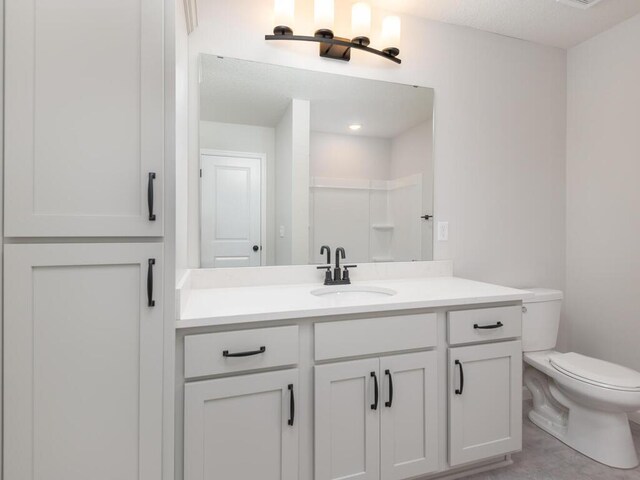 bathroom featuring toilet, a shower, and vanity