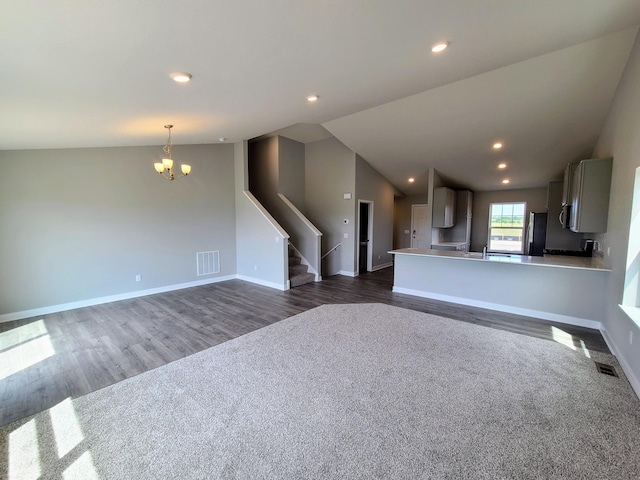 unfurnished living room featuring dark wood-type flooring, lofted ceiling, and a chandelier