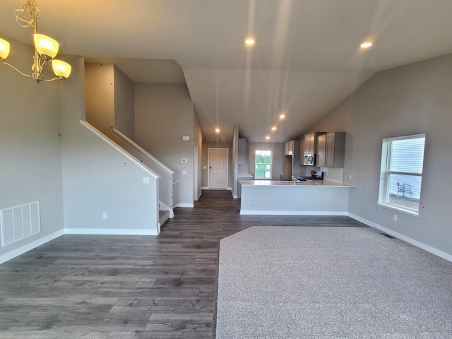 kitchen featuring vaulted ceiling, pendant lighting, kitchen peninsula, stainless steel appliances, and an inviting chandelier