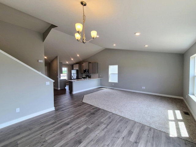 unfurnished living room with dark wood-type flooring, a chandelier, and vaulted ceiling