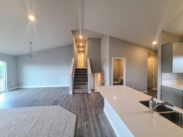 kitchen featuring sink, hanging light fixtures, tasteful backsplash, dark hardwood / wood-style flooring, and vaulted ceiling