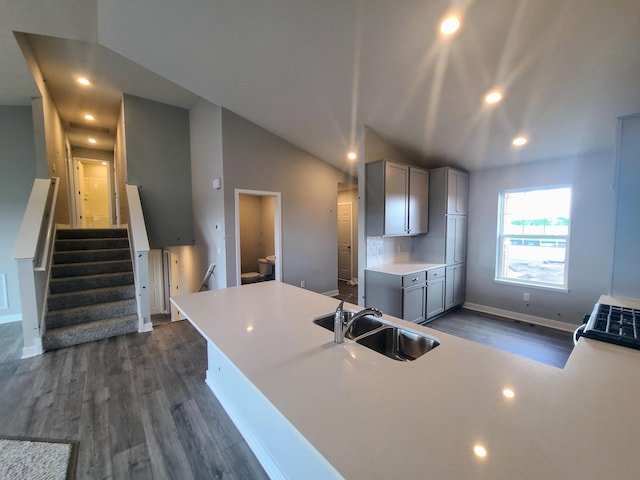 kitchen featuring lofted ceiling, sink, dark hardwood / wood-style flooring, gray cabinets, and decorative backsplash