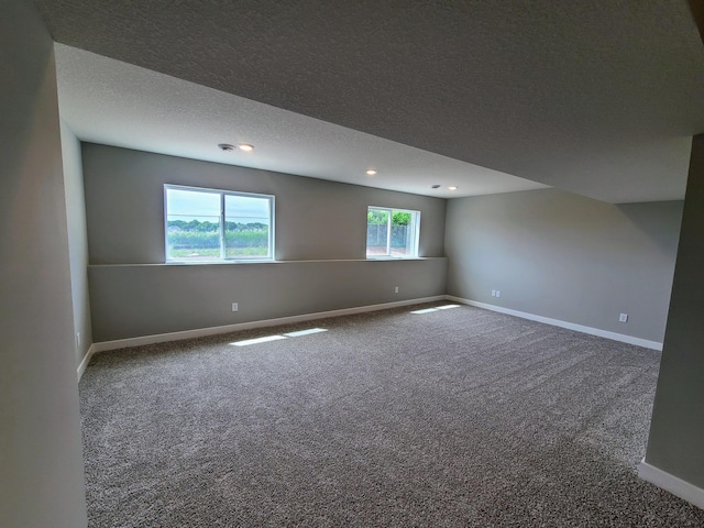 unfurnished room with a healthy amount of sunlight, carpet flooring, and a textured ceiling