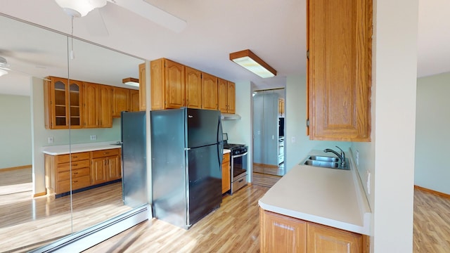 kitchen featuring ceiling fan, sink, stainless steel range with gas stovetop, black refrigerator, and baseboard heating