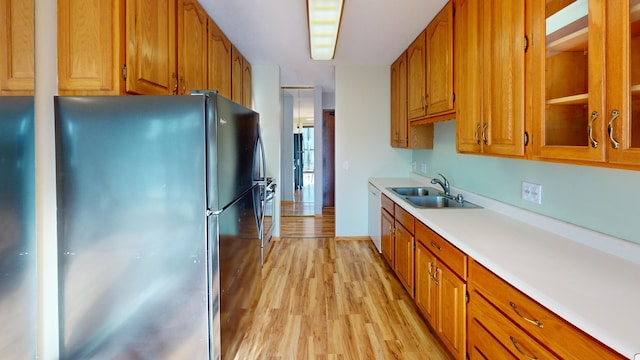 kitchen featuring black refrigerator, dishwasher, sink, and light hardwood / wood-style floors