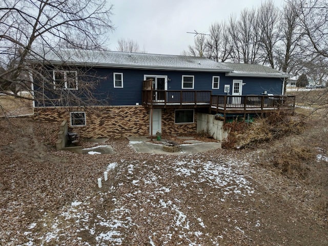 snow covered back of property featuring a wooden deck and a fire pit