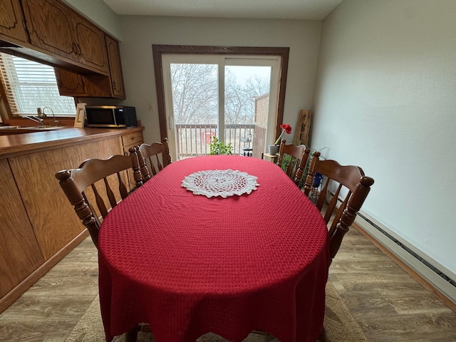 dining area featuring a baseboard heating unit, sink, and light hardwood / wood-style floors