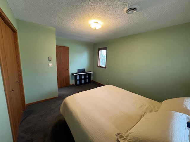 bedroom with a textured ceiling, a closet, and dark colored carpet