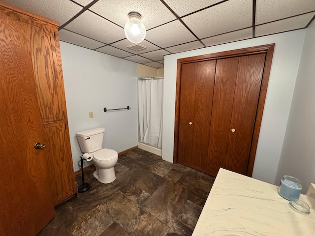 bathroom featuring toilet, a shower with curtain, a drop ceiling, and vanity