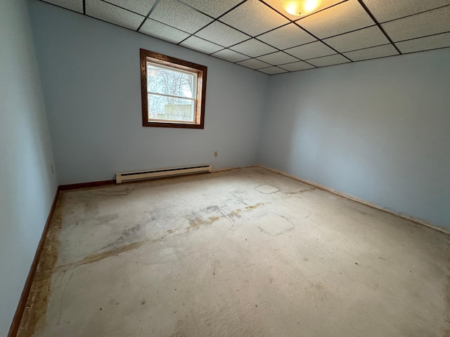 unfurnished room featuring baseboard heating and a drop ceiling