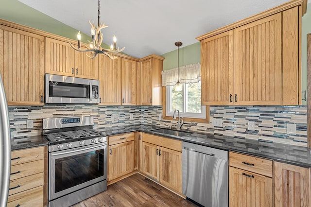 kitchen with a notable chandelier, sink, stainless steel appliances, and pendant lighting