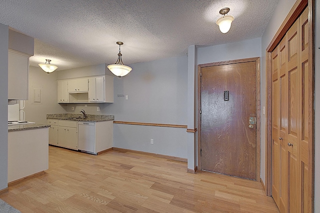 kitchen featuring white cabinetry, dishwasher, sink, hanging light fixtures, and a textured ceiling