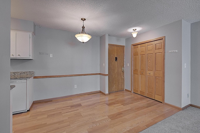 unfurnished dining area featuring light hardwood / wood-style floors and a textured ceiling