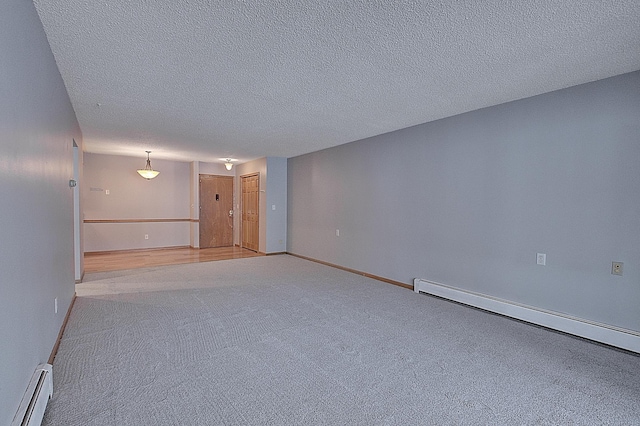 carpeted empty room with a textured ceiling and a baseboard heating unit