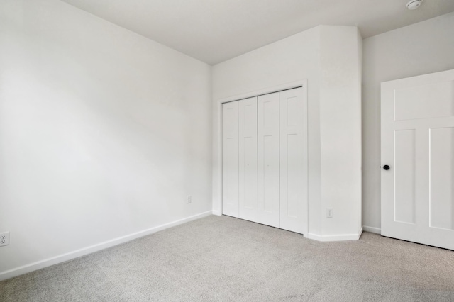 unfurnished bedroom featuring a closet and light carpet