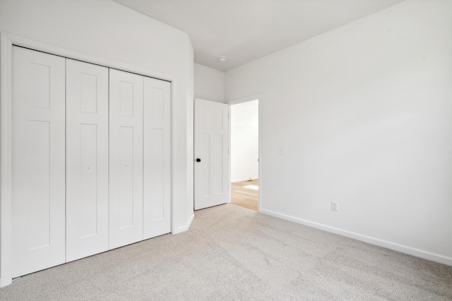 unfurnished bedroom with a closet and light colored carpet