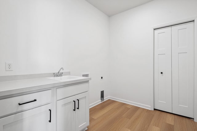 clothes washing area featuring light wood-type flooring, cabinets, sink, hookup for an electric dryer, and hookup for a washing machine