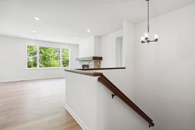 staircase with a notable chandelier, a fireplace, and wood-type flooring