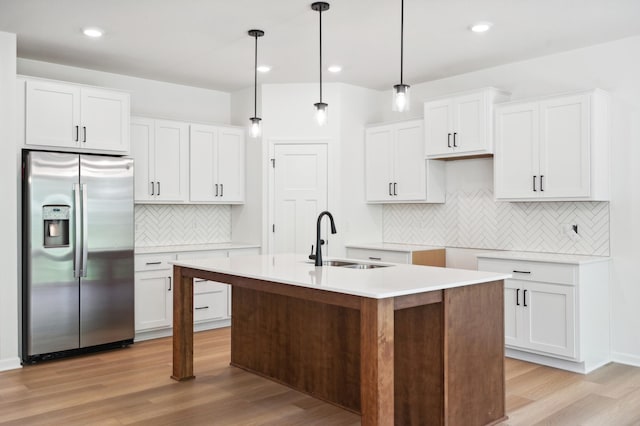 kitchen with sink, hanging light fixtures, white cabinets, and stainless steel refrigerator with ice dispenser