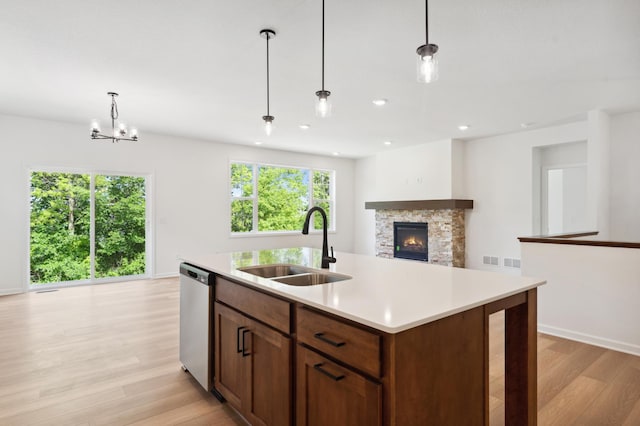 kitchen with sink, stainless steel dishwasher, pendant lighting, and an island with sink