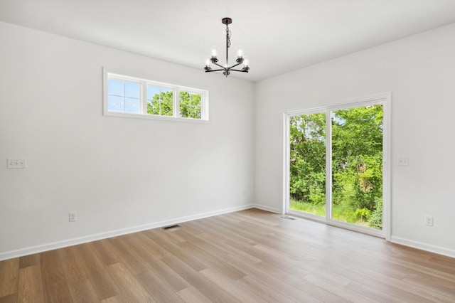 empty room with a chandelier and light wood-type flooring