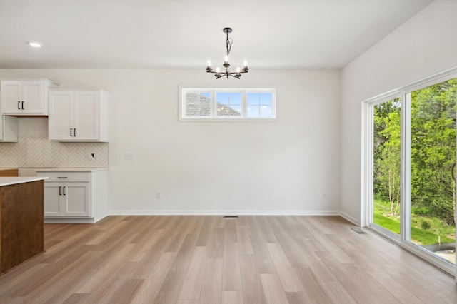 kitchen with white cabinets, backsplash, a wealth of natural light, and pendant lighting