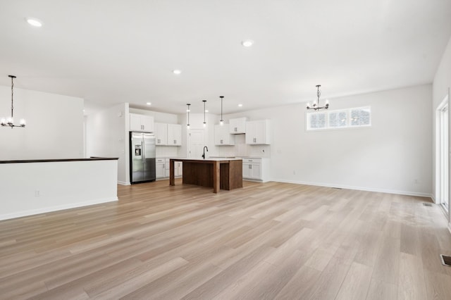 unfurnished living room featuring sink, an inviting chandelier, and light hardwood / wood-style flooring