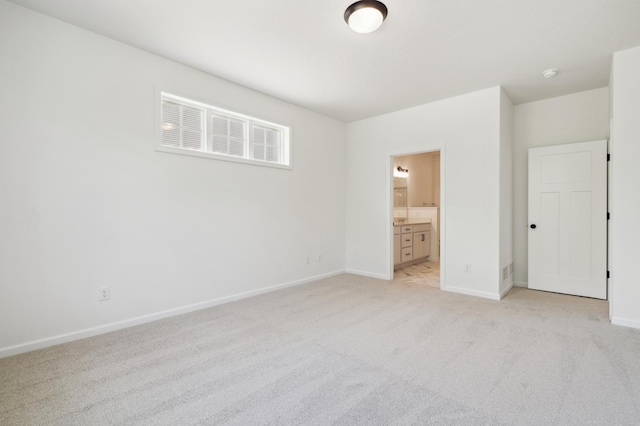 unfurnished bedroom featuring light colored carpet and ensuite bath