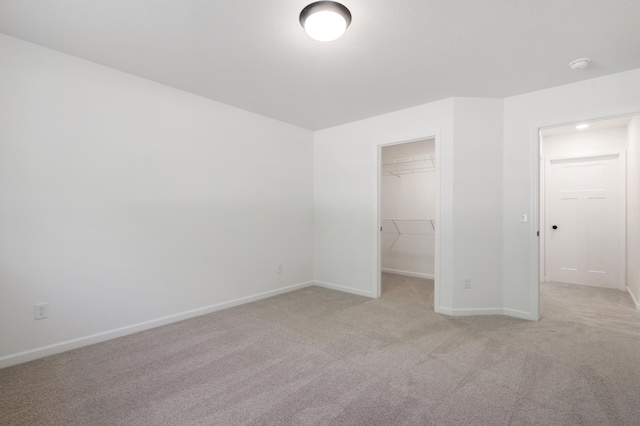 unfurnished bedroom featuring light colored carpet, a closet, and a walk in closet