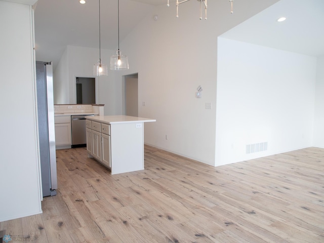 kitchen with decorative light fixtures, tasteful backsplash, a kitchen island, light hardwood / wood-style flooring, and appliances with stainless steel finishes