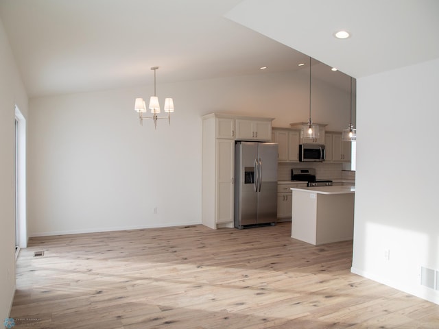 kitchen with appliances with stainless steel finishes, decorative light fixtures, white cabinetry, tasteful backsplash, and light hardwood / wood-style floors