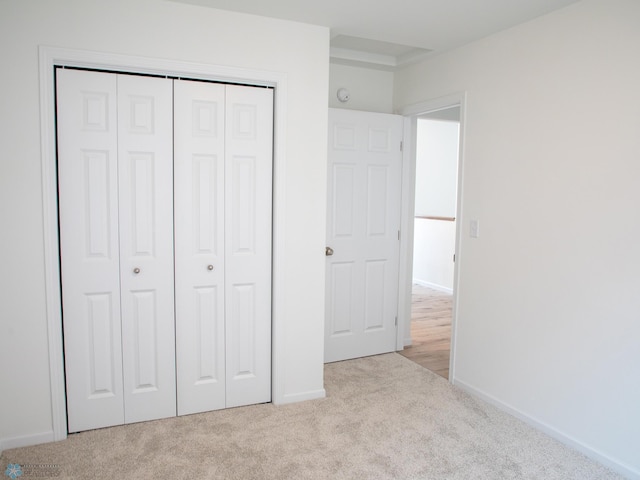 unfurnished bedroom with light colored carpet and a closet