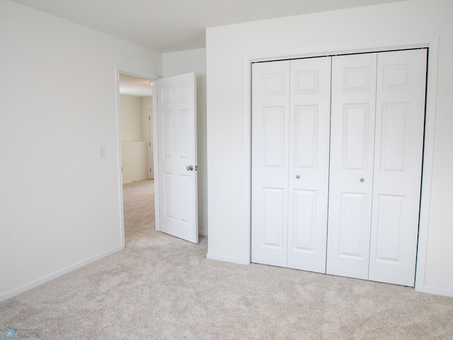 unfurnished bedroom with light carpet and a closet