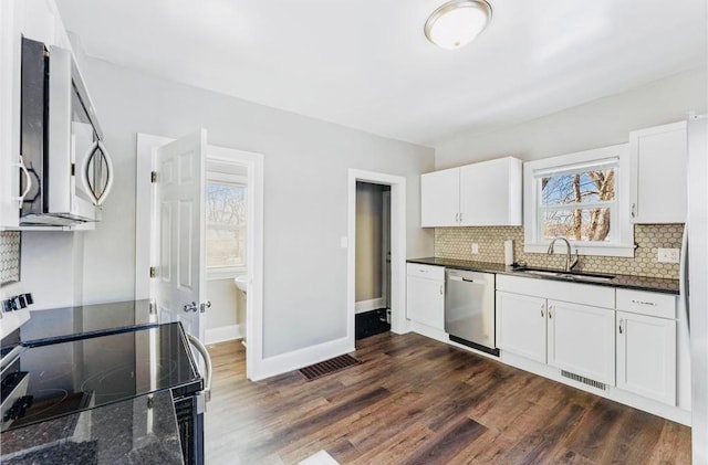 kitchen featuring appliances with stainless steel finishes, dark stone countertops, white cabinetry, and sink