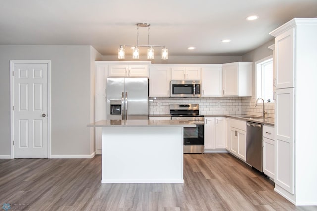 kitchen with decorative light fixtures, sink, white cabinetry, a kitchen island, and stainless steel appliances