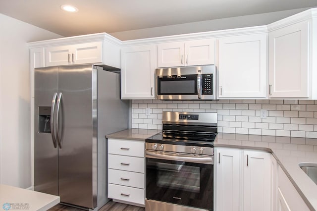 kitchen featuring white cabinets, decorative backsplash, dark wood-type flooring, and appliances with stainless steel finishes