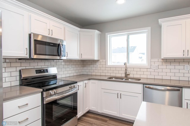 kitchen with sink, white cabinets, decorative backsplash, and stainless steel appliances