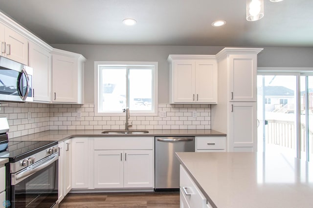 kitchen featuring appliances with stainless steel finishes, white cabinetry, decorative backsplash, sink, and plenty of natural light