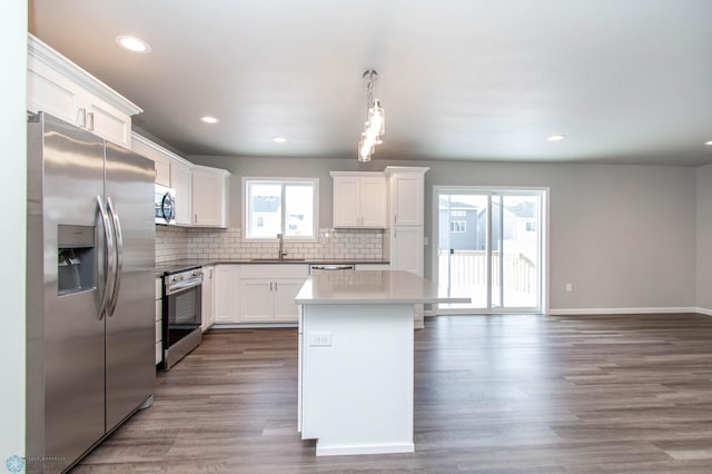 kitchen featuring a center island, appliances with stainless steel finishes, hanging light fixtures, white cabinets, and sink