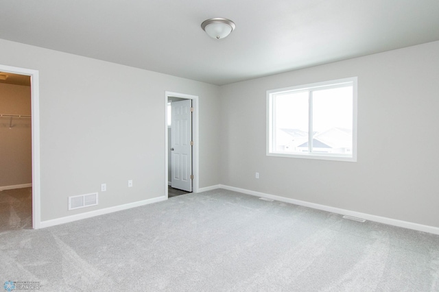 unfurnished bedroom featuring carpet flooring, a closet, and a walk in closet