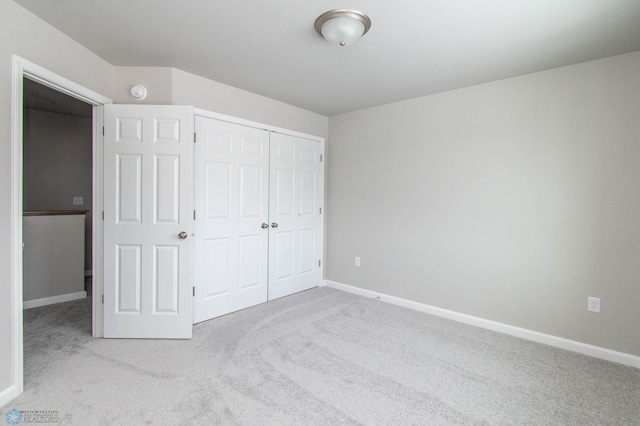 unfurnished bedroom with light carpet and a closet