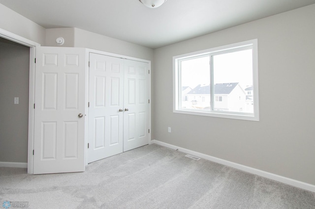 unfurnished bedroom with light carpet and a closet